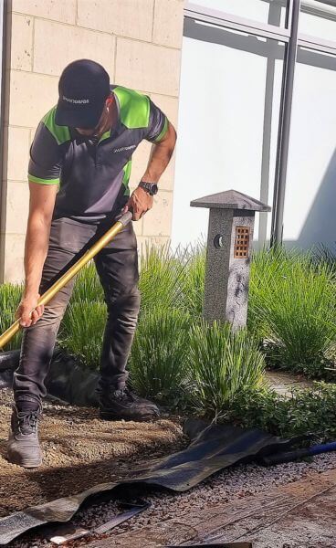 SmartGrass installer expertly lays down synthetic turf in a residential garden, showcasing the high-quality, realistic appearance of the product.