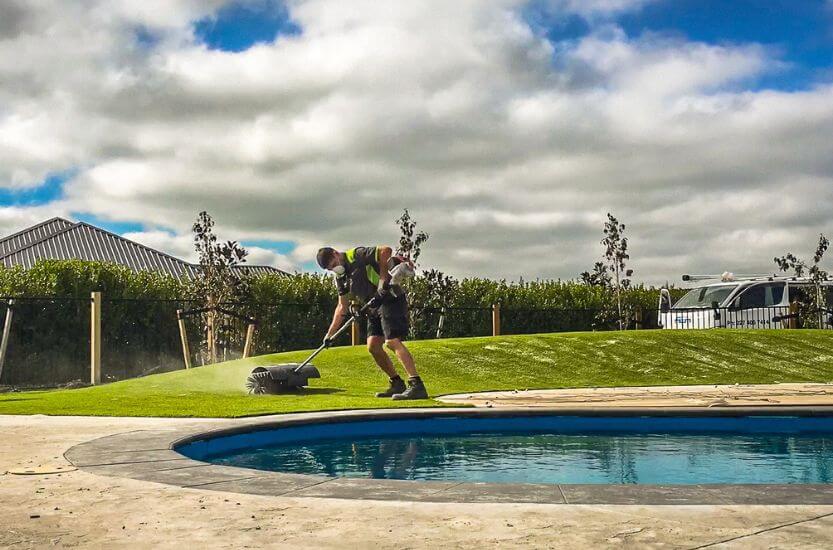 Power broom in use during artificial grass installation before silica sand is applied